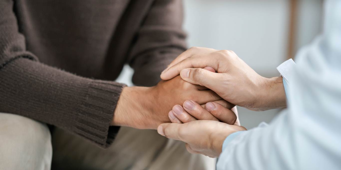 image of two people holding hands, providing support.